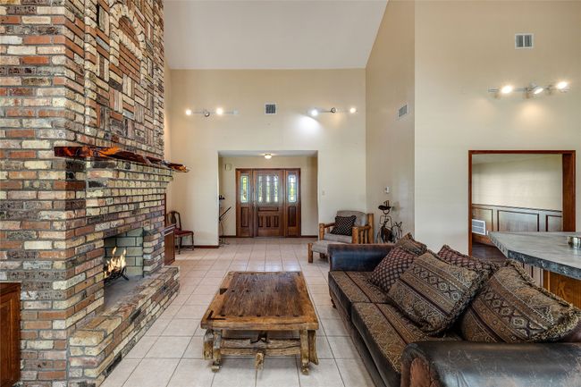 Living room featuring a towering ceiling, light tile patterned floors, and a fireplace | Image 5