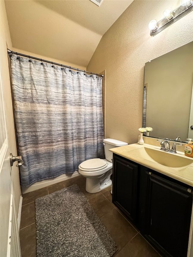 Full bath featuring vanity, tile patterned flooring, toilet, lofted ceiling, and a textured wall | Image 12