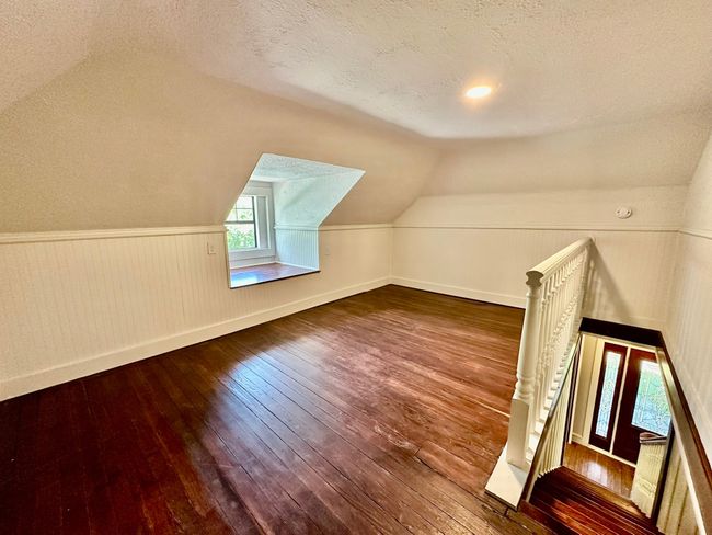 Bonus room with wood-type flooring, a textured ceiling, lofted ceiling, and a wainscoted wall | Image 17