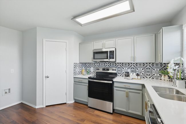 Kitchen featuring appliances with stainless steel finishes, gray cabinets, light countertops, tasteful backsplash, and dark wood-type​​‌​​​​‌​​‌‌​‌‌​​​‌‌​​‌‌​‌​​​​​‌ flooring | Image 14