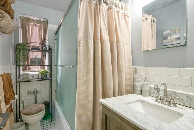 Bathroom featuring tile walls, vanity, shower / bath combo with shower curtain, and wainscoting | Image 17