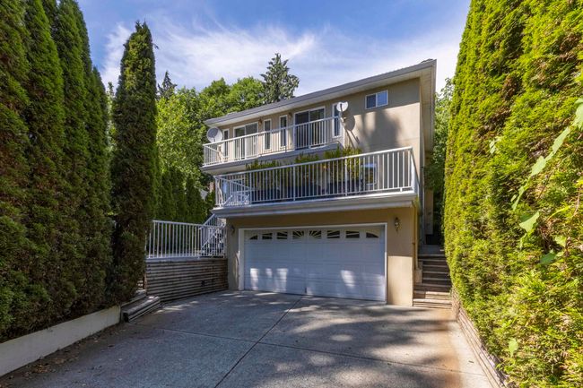 View of back of house with stairway, a balcony, driveway, an attached garage, and stucco siding | Image 29