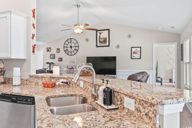 Kitchen with stainless steel dishwasher, ceiling fan, vaulted ceiling, light stone countertops, and white cabinetry | Image 15