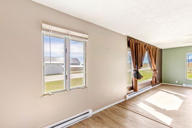 Empty room with baseboards, wood finished floors, a textured ceiling, and a baseboard radiator | Image 12
