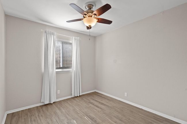 Second bedroom with ceiling fan and window treatments. | Image 23