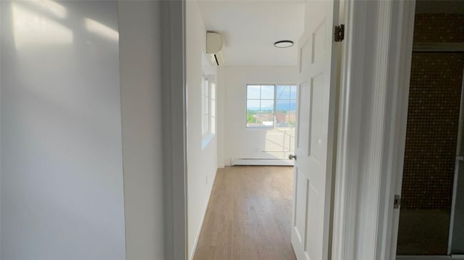 Hallway with light wood finished floors, a baseboard radiator, and a wall unit AC | Image 17
