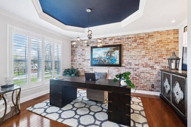 Dedicated office space on the main level. Brick accent wall, dramatic ceiling detail, and natural light create a standout workspace. | Image 12
