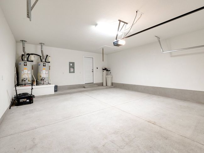 Garage with gas water heater, electric panel, and a garage door opener | Image 33
