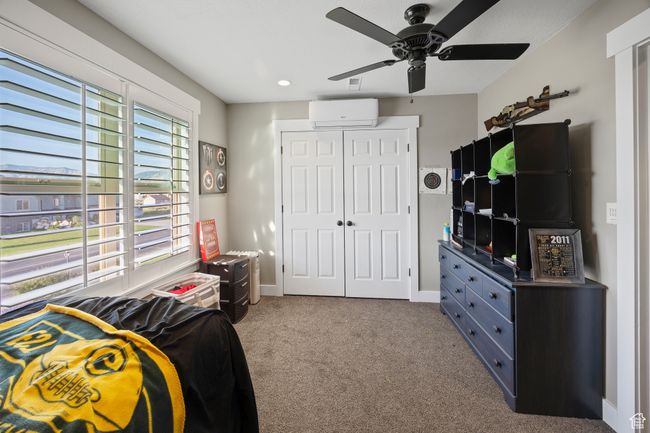 Bedroom with a wall mounted AC, a closet, carpet floors, ceiling fan, and baseboards | Image 57