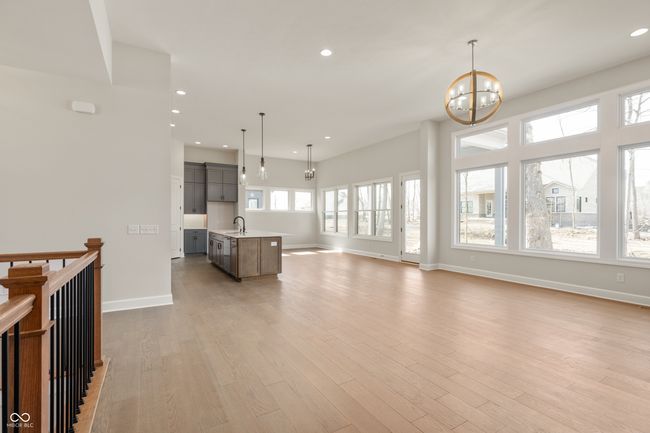 Family room with light wood-style floors, recessed lighting, and stairway leading to finished basement. | Image 13