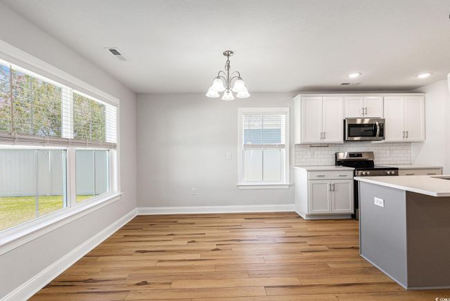 Kitchen featuring stainless steel appliances, a chandelier, healthy amount of natural light, light wood-style floors, and recessed lighting | Image 9