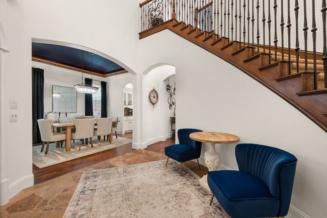 View from foyer looking into the formal dining room. Stone tile floors, arched walkways, and a high ceiling | Image 6