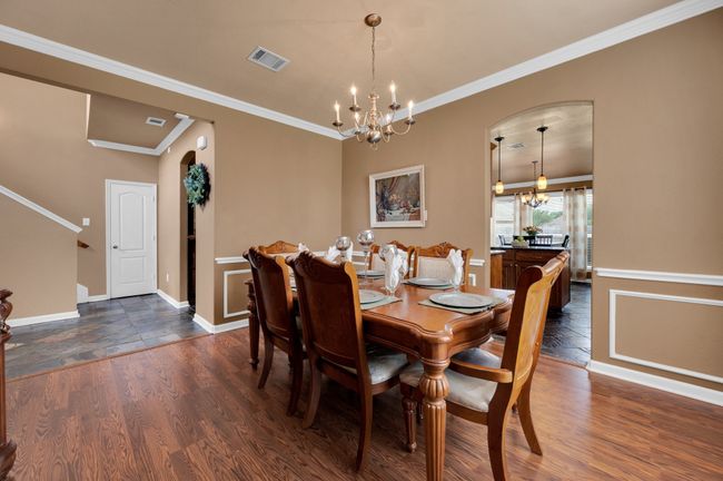 Dining room featuring a chandelier, dark wood-style flooring, ornamental molding, and arched walkways | Image 11