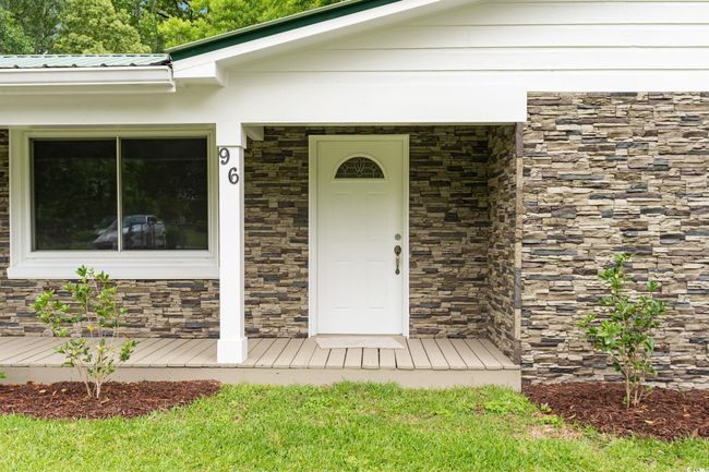 Doorway to property featuring stone siding and metal roof | Image 17