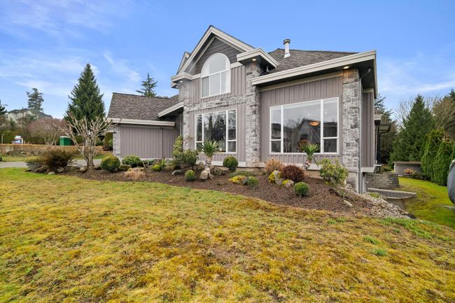 Exterior space featuring a lawn, stone siding, and a shingled roof | Image 4