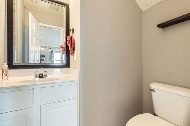 Half bath featuring a textured ceiling, toilet, and vanity | Image 13