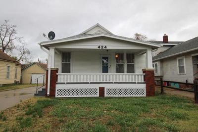 Bungalow-style home with a front yard, covered porch, an outdoor structure, and a garage | Image 1