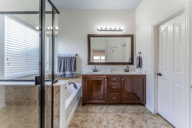 Bathroom featuring a bath, double vanity, a shower with door, and tile patterned flooring | Image 14