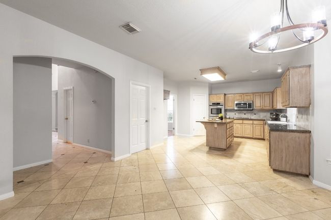 Kitchen with stainless steel microwave, a kitchen island, arched walkways, baseboards, and a sink | Image 12