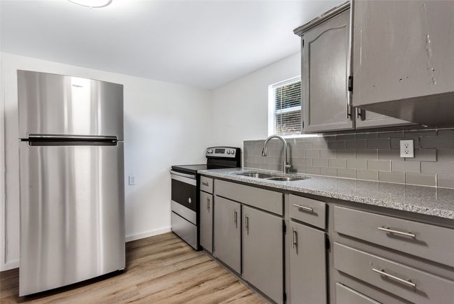 Kitchen featuring stainless steel appliances, gray cabinetry, decorative backsplash, and light wood-style floors | Image 29