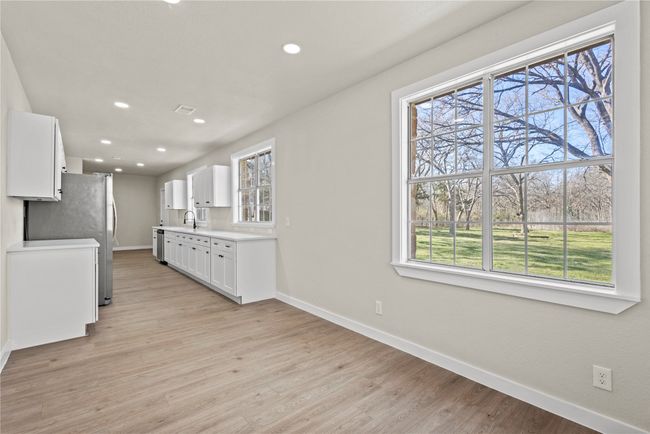 Kitchen featuring light countertops, light wood-style flooring, baseboards, and white cabinetry | Image 5