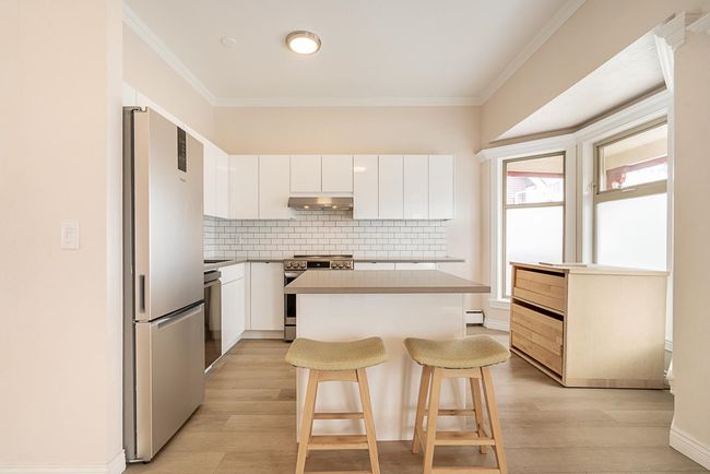 Kitchen with stainless steel appliances, under cabinet range hood, backsplash, a kitchen breakfast bar, and crown molding | Image 11