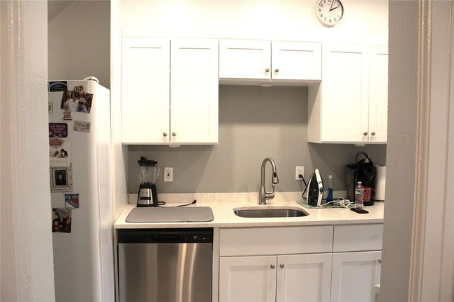 Kitchen with dishwasher, a sink, white cabinets, freestanding refrigerator, and light countertops | Image 5
