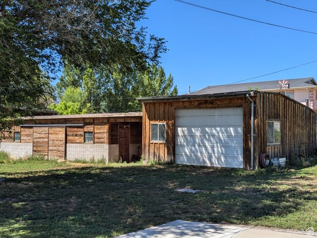 View of front of home with board and batten siding, an outdoor structure, a garage, and driveway | Image 27
