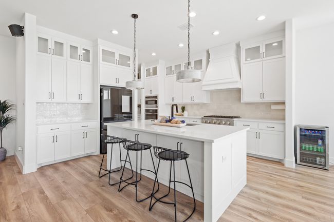 Kitchen with wine cooler, premium range hood, decorative backsplash, a center island with sink, and recessed lighting | Image 4