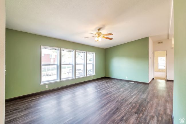 Empty room featuring dark wood-type flooring, ceiling fan, and baseboards | Image 7