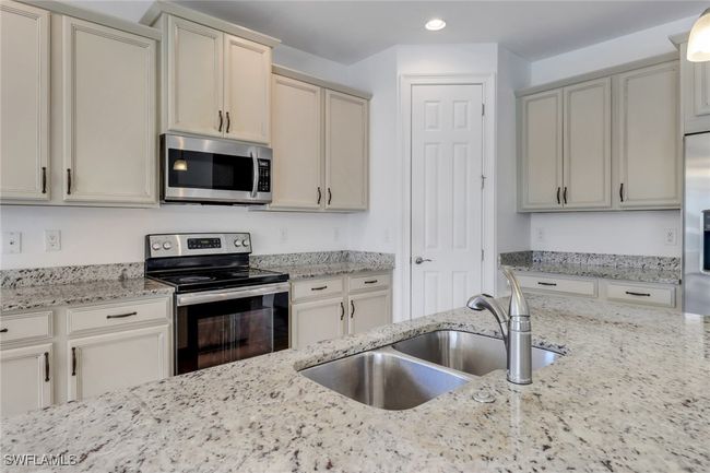 Kitchen with appliances with stainless steel finishes, a sink, recessed lighting, and light stone counters | Image 25
