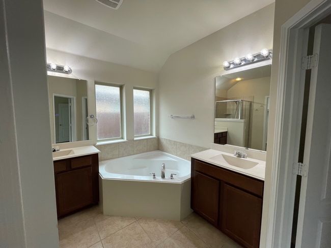 Bathroom with vaulted ceiling, a shower stall, tile patterned flooring, a garden tub, and two vanities | Image 13