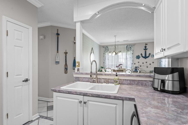 Kitchen with a sink, ornamental molding, white cabinetry, a chandelier, and light tile patterned floors | Image 18