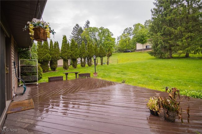 Wooden deck featuring a lawn and view of scattered trees | Image 7