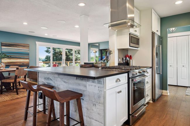 White kitchen with a great eating area that flows into the living room and opens out to the deck. An abundance of well-planned storage in the kitchen. This kitchen is sure to be a chef’s delight! | Image 13