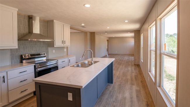 Kitchen featuring wall chimney range hood, stainless steel range with electric stovetop, plenty of natural light, recessed lighting, and backsplash | Image 21