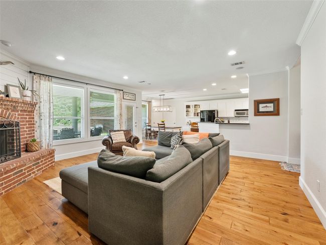 Living area with crown molding, light wood-style floors, a brick fireplace, recessed lighting, and a textured ceiling | Image 4