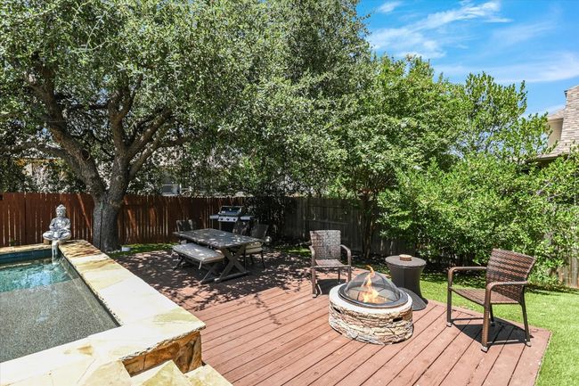 Back deck with firepit and picnic table that is under a shade tree. | Image 25
