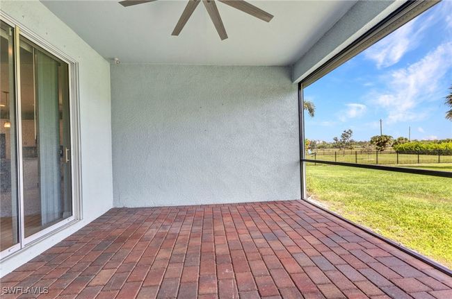 View of screened in patio with electric shutter and a ceiling fan | Image 5