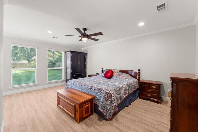 This inviting bedroom features two windows overlooking the backyard. The room has a ceiling fan and recessed lighting, creating a comfortable, airy atmosphere. | Image 19
