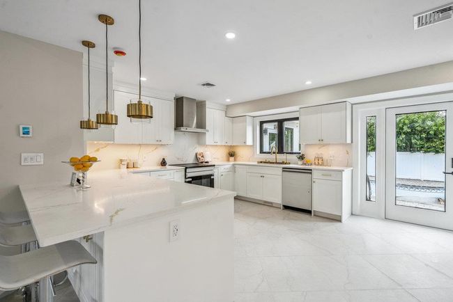 Kitchen featuring a peninsula, stainless steel Appliances, backsplash, white Custom made cabinetry | Image 6