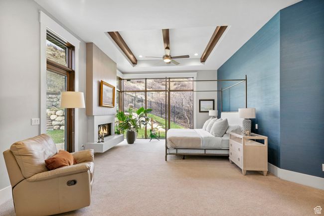 Carpeted bedroom featuring a tray ceiling and a lit fireplace | Image 35