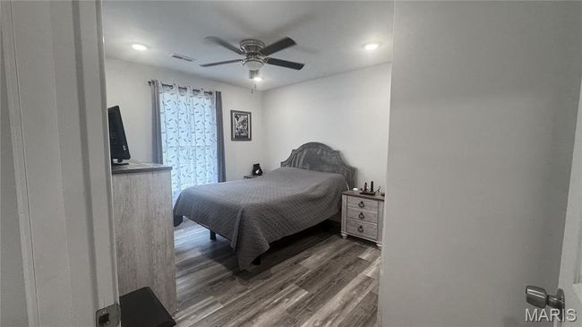 Bedroom with dark wood-type flooring and ceiling fan | Image 7