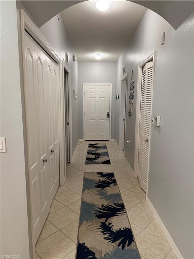 Hall with light tile patterned floors, arched walkways, and baseboards | Image 6