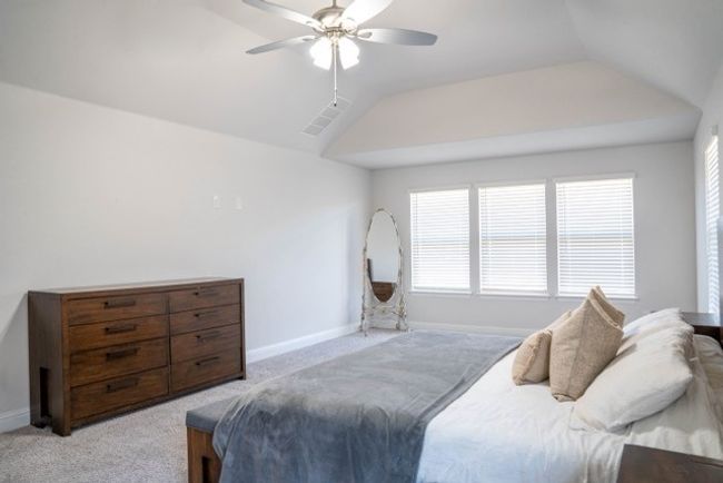 Bedroom with light carpet, baseboards, visible vents, lofted ceiling, and ceiling fan | Image 15