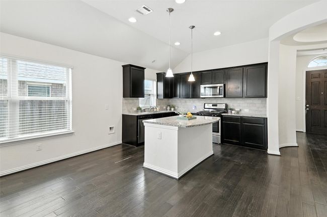 Kitchen with appliances with stainless steel finishes, backsplash, a kitchen island, pendant lighting, and lofted ceiling | Image 11