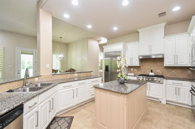 Gourmet clean white kitchen with contrasting granite island bar, stainless steel appliances and a gas cooking range! | Image 17