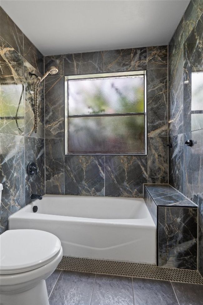 Bathroom featuring washtub / shower combination and tile walls | Image 17