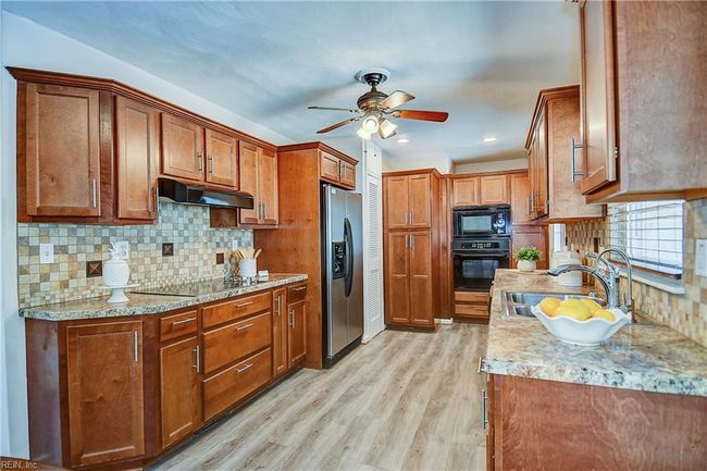 Kitchen features ceramic tile backsplashes and solid wood cabinets. | Image 21