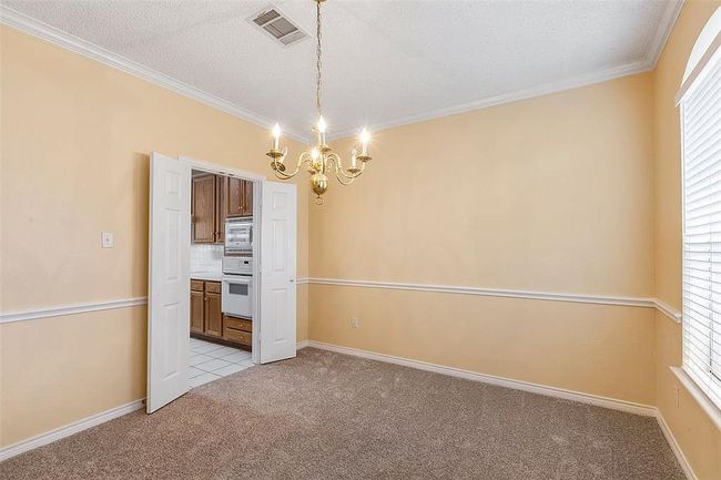 Unfurnished dining area featuring visible vents, a chandelier, light colored carpet, and crown molding | Image 9